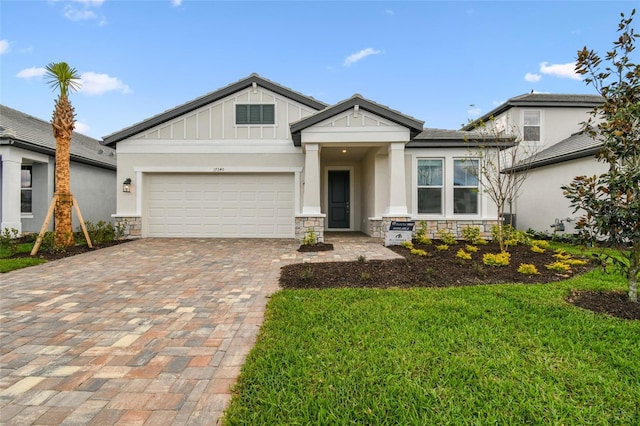 view of front facade featuring a garage, stone siding, decorative driveway, a front lawn, and board and batten siding