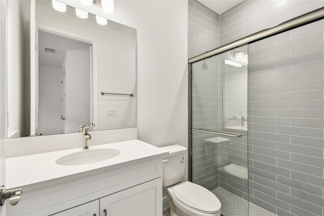 bathroom with visible vents, a tile shower, and toilet