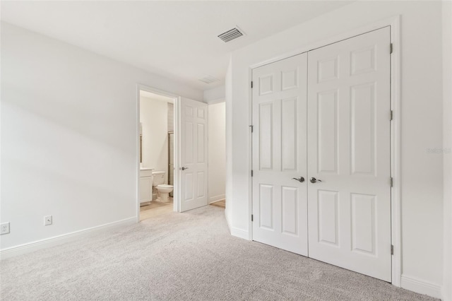 unfurnished bedroom featuring a closet, light colored carpet, visible vents, ensuite bathroom, and baseboards