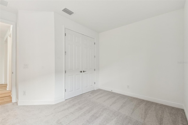 unfurnished bedroom with carpet floors, a closet, and visible vents