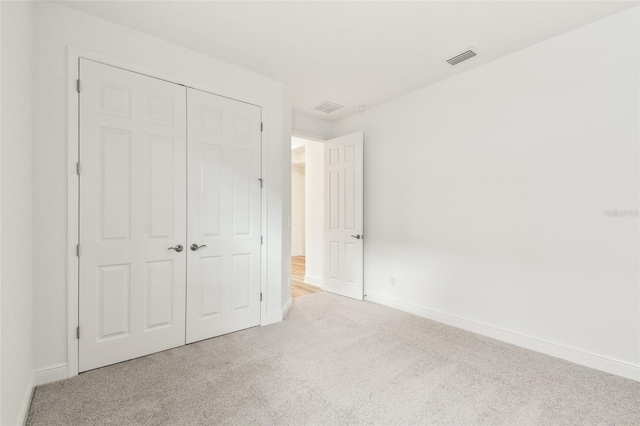 unfurnished bedroom with baseboards, a closet, visible vents, and carpet flooring