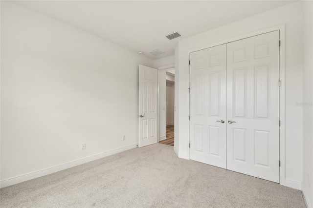 unfurnished bedroom with baseboards, carpet, visible vents, and a closet