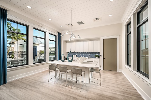 kitchen with light countertops, visible vents, backsplash, white cabinets, and a kitchen bar