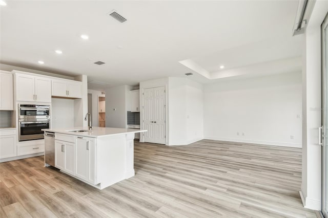 kitchen with light wood-style floors, recessed lighting, light countertops, and a sink