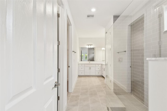 bathroom featuring tile patterned flooring, visible vents, vanity, and a walk in shower