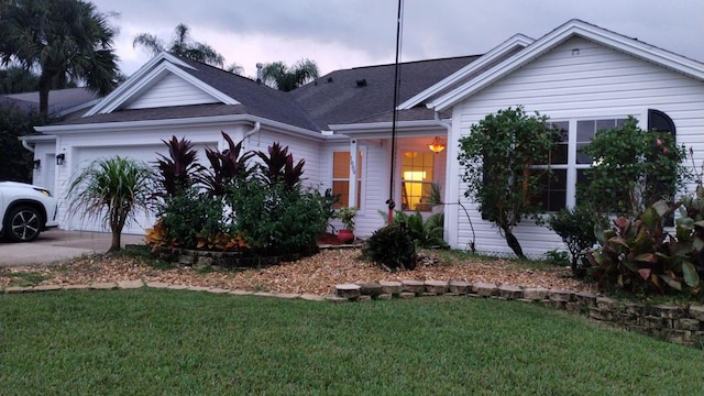 view of front of home featuring a garage, driveway, a front lawn, and roof with shingles