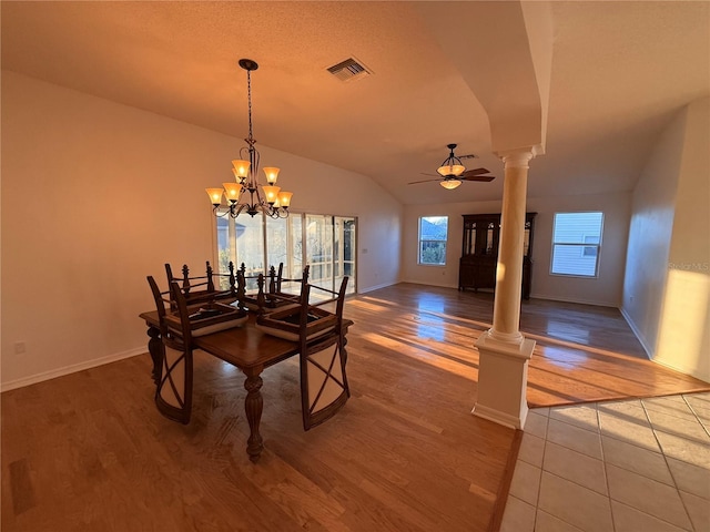 dining space featuring hardwood / wood-style floors, ceiling fan with notable chandelier, ornate columns, and lofted ceiling