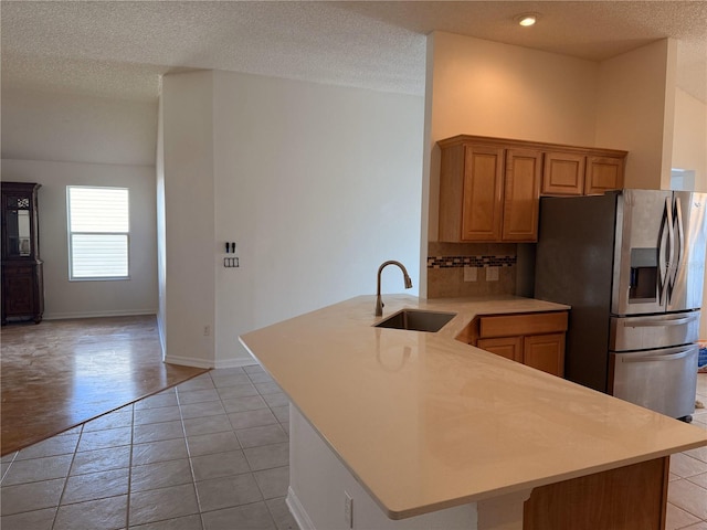 kitchen featuring stainless steel fridge with ice dispenser, kitchen peninsula, sink, and a textured ceiling