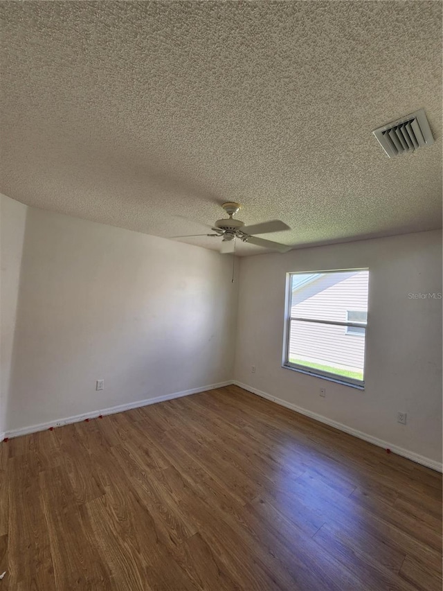 empty room featuring ceiling fan, dark wood-type flooring, and a textured ceiling