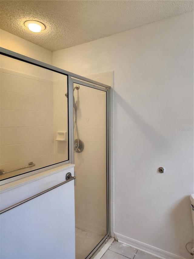 bathroom with a textured ceiling, toilet, and walk in shower