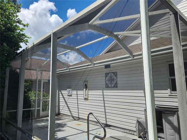 view of side of property with glass enclosure and a patio