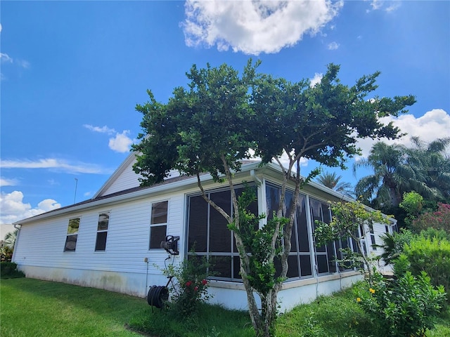 view of property exterior featuring a lawn and a sunroom