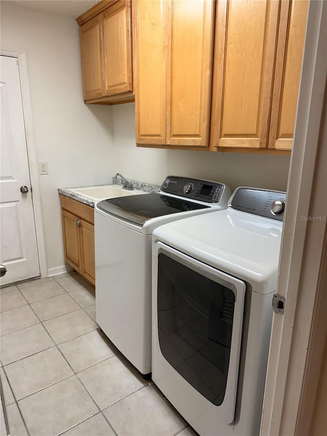 clothes washing area with cabinets, sink, light tile patterned floors, and washer and dryer