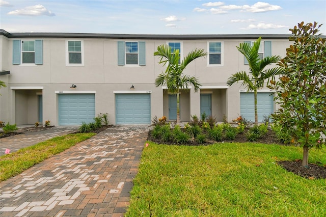 multi unit property featuring a front lawn and a garage