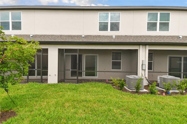 rear view of house with cooling unit and a yard