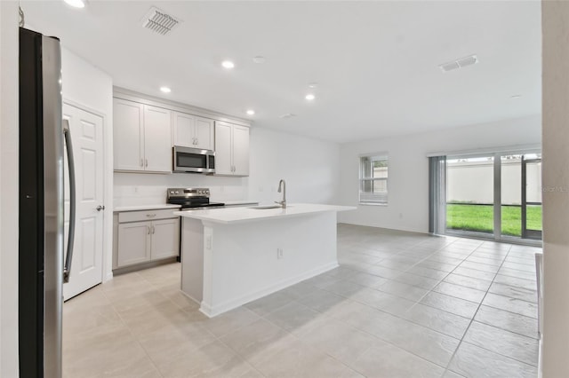 kitchen with an island with sink, light tile patterned flooring, sink, and stainless steel appliances