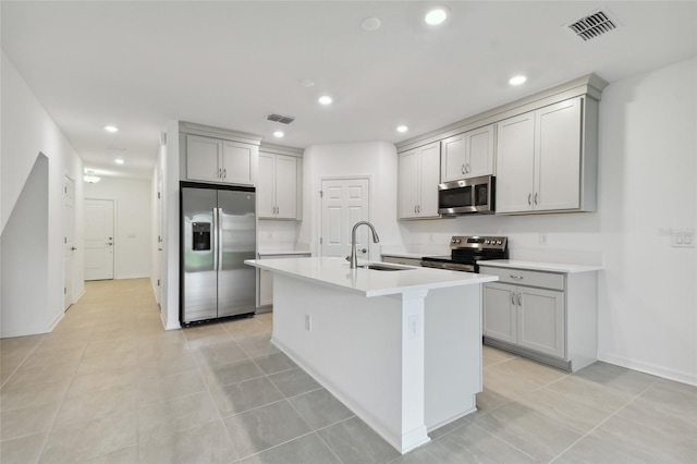 kitchen featuring a center island with sink, appliances with stainless steel finishes, sink, and gray cabinetry