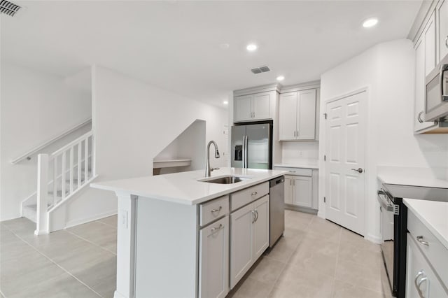 kitchen featuring sink, an island with sink, gray cabinetry, appliances with stainless steel finishes, and light tile patterned floors