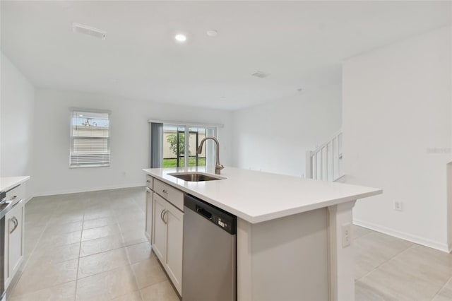 kitchen with white cabinets, light tile patterned floors, stainless steel appliances, a kitchen island with sink, and sink