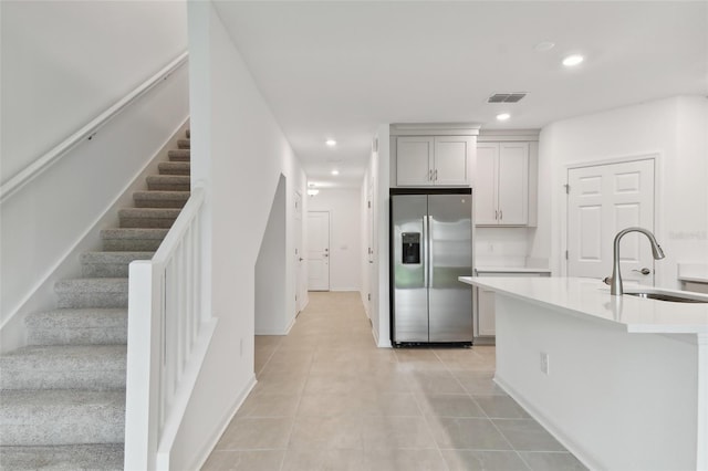 kitchen featuring stainless steel refrigerator with ice dispenser, light tile patterned flooring, and sink