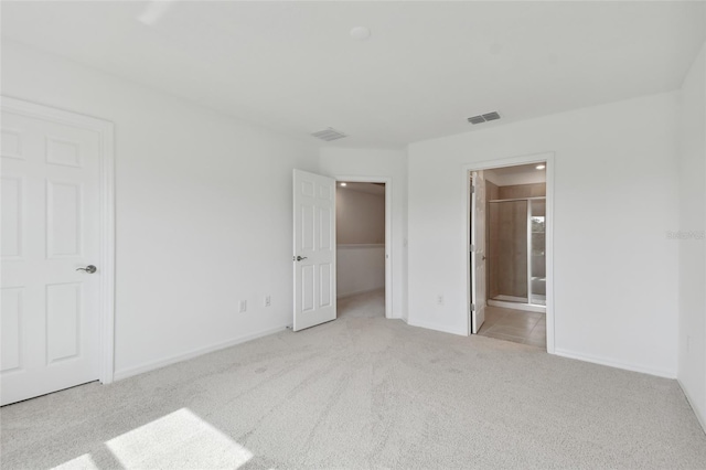 unfurnished bedroom with light carpet and connected bathroom