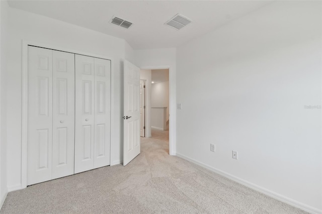 unfurnished bedroom featuring light colored carpet and a closet