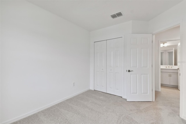 unfurnished bedroom featuring sink, light carpet, and a closet