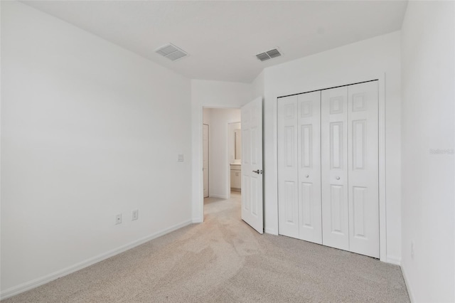 unfurnished bedroom with light colored carpet and a closet