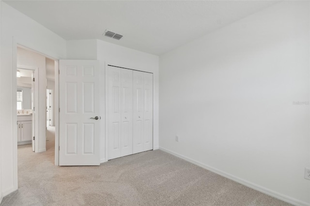 unfurnished bedroom with a closet and light colored carpet