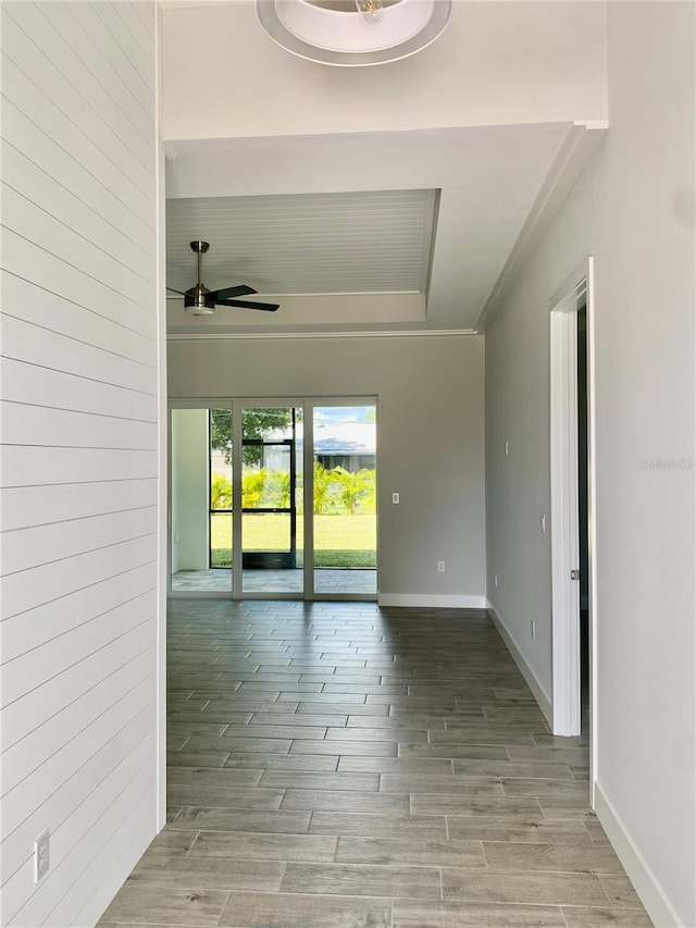 empty room with wood finish floors, baseboards, ceiling fan, and a raised ceiling