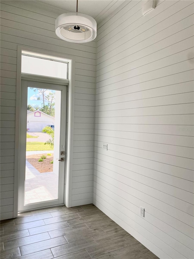 doorway with wood walls and hardwood / wood-style flooring