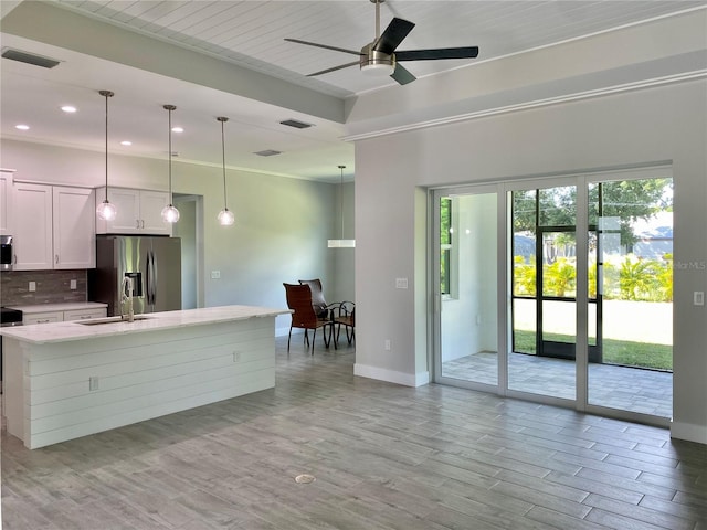 kitchen with light wood-type flooring, white cabinets, hanging light fixtures, appliances with stainless steel finishes, and ceiling fan