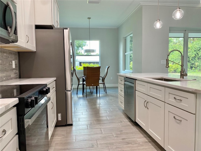 kitchen with hanging light fixtures, white cabinetry, stainless steel appliances, and a wealth of natural light