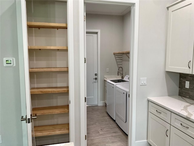 washroom with washer and clothes dryer, light hardwood / wood-style floors, and cabinets