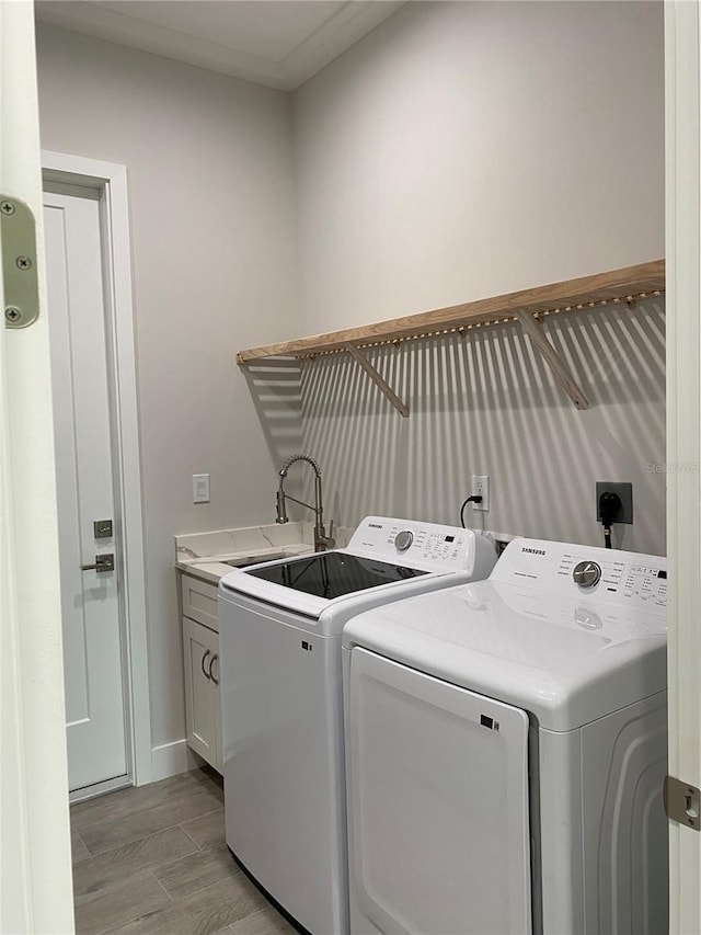 washroom featuring light wood-type flooring, baseboards, a sink, cabinet space, and washing machine and dryer