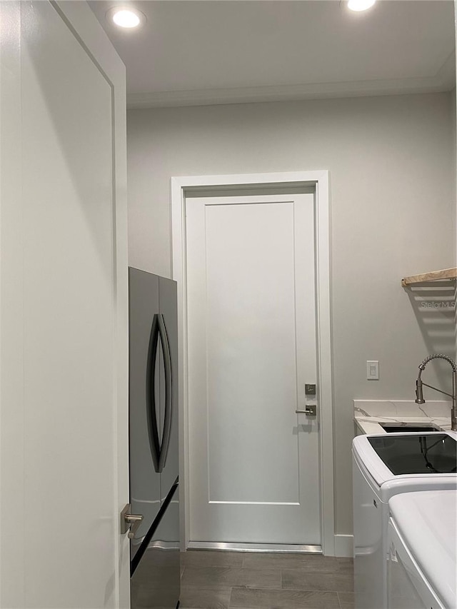 clothes washing area featuring washing machine and clothes dryer, laundry area, recessed lighting, a sink, and dark wood-style floors