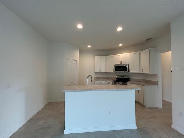 kitchen with stainless steel appliances, light countertops, visible vents, white cabinetry, and a kitchen island with sink