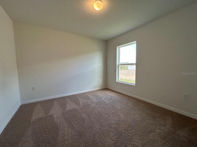 empty room featuring baseboards and carpet flooring