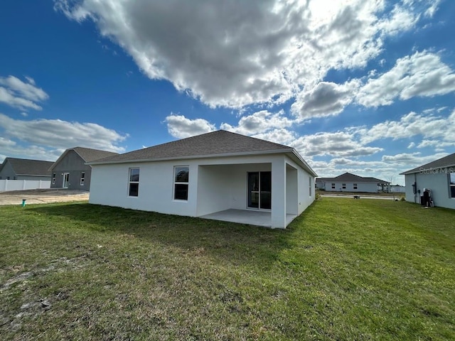 back of property with stucco siding, a lawn, and a patio