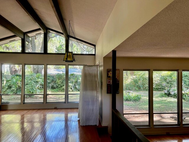 unfurnished sunroom with vaulted ceiling with beams