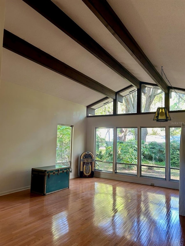 unfurnished living room featuring wood-type flooring and lofted ceiling with beams