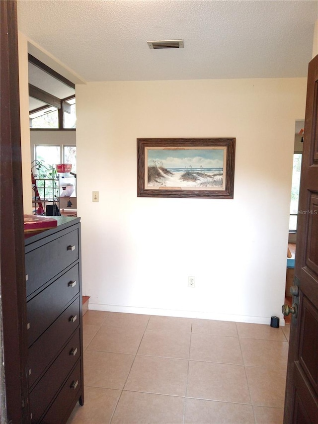 hallway featuring a textured ceiling and light tile patterned floors