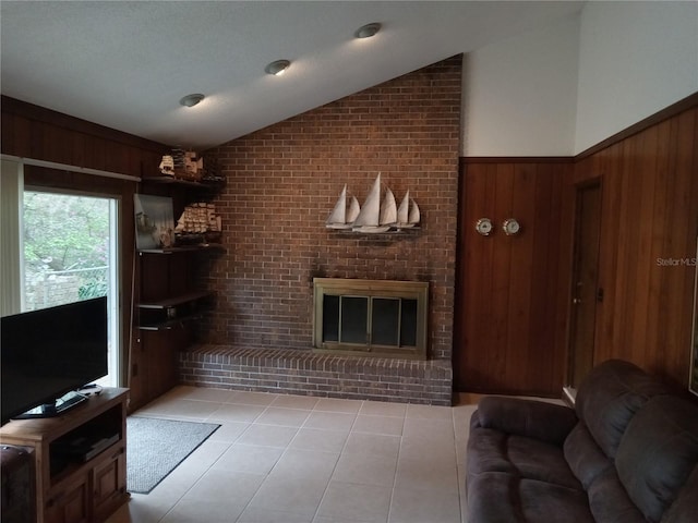 living room with vaulted ceiling, a brick fireplace, and wooden walls