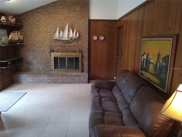 living room featuring lofted ceiling, a fireplace, wood walls, and light tile patterned flooring