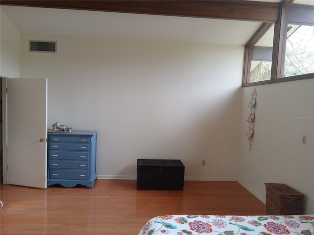 bedroom with beamed ceiling and light hardwood / wood-style floors