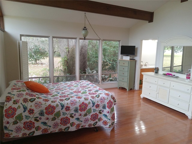 bedroom with hardwood / wood-style flooring and vaulted ceiling with beams