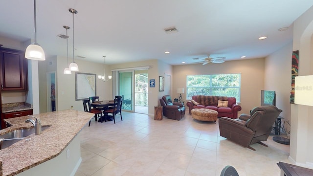 tiled living room featuring ceiling fan with notable chandelier and sink