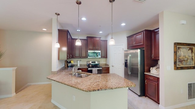 kitchen with light stone counters, pendant lighting, sink, kitchen peninsula, and appliances with stainless steel finishes