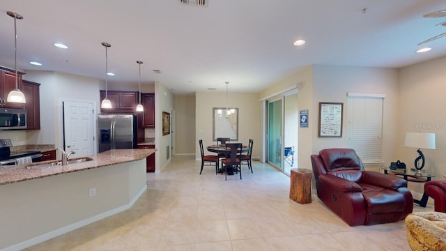 interior space with pendant lighting, light tile patterned flooring, sink, stainless steel appliances, and light stone countertops