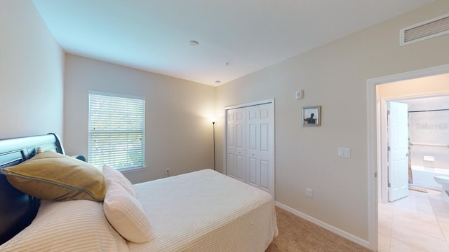 bedroom featuring connected bathroom, light colored carpet, and a closet